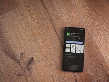 Lod, Israel - July 16,2023: AdGuard app play store page on smartphone on wooden background. Top view flat lay with copy space.