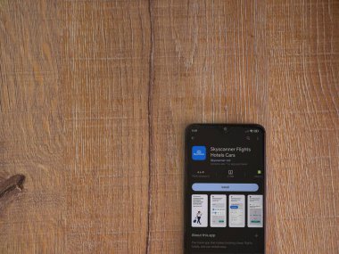 Lod, Israel - July 16,2023: Skyscanner app play store page on smartphone on wooden background. Top view flat lay with copy space.