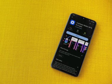 Lod, Israel - 16 Temmuz 2023: Cüzdan tabanı uygulaması oyun sayfası sarı kumaş arka planda akıllı telefon. Üst görünüm düzlüğü kopyalama alanı ile yatıyordu.