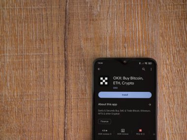 Lod, Israel - 16 Temmuz 2023: OKX uygulama oyun mağazası sayfası ahşap arka planda akıllı telefon. Üst görünüm düzlüğü kopyalama alanı ile yatıyordu.