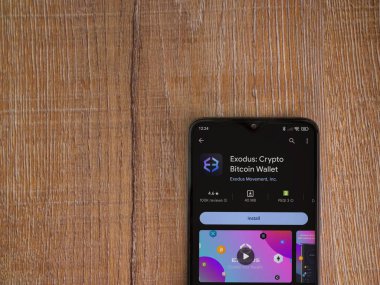 Lod, Israel - 16 Temmuz 2023: Exodus app playshop page on smartphone on wood background. Üst görünüm düzlüğü kopyalama alanı ile yatıyordu.