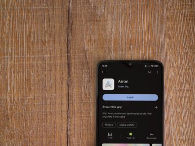Lod, Israel - 16 Temmuz 2023: AirTM uygulama oyun mağazası sayfası ahşap zemin üzerinde akıllı telefon. Üst görünüm düzlüğü kopyalama alanı ile yatıyordu.