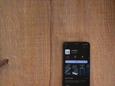 Lod, Israel - 16 Temmuz 2023: Ahşap arka planda akıllı telefon üzerine Avatrade uygulaması oyun mağazası sayfası. Üst görünüm düzlüğü kopyalama alanı ile yatıyordu.