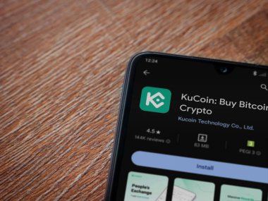 Lod, Israel - 16 Temmuz 2023: KuCoin uygulama oyun mağazası sayfası ahşap zemin üzerinde akıllı telefon. Üst görünüm düzlüğü kopyalama alanı ile yatıyordu.