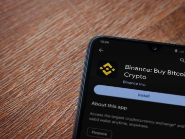 Lod, Israel - 16 Temmuz 2023: Binance uygulama oyun mağazası sayfası ahşap arka planda akıllı telefon. Üst görünüm düzlüğü kopyalama alanı ile yatıyordu.