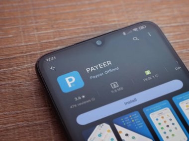 Lod, Israel - 16 Temmuz 2023: PaYEER uygulama oyun mağazası sayfası ahşap zemin üzerinde akıllı telefon. Üst görünüm düzlüğü kopyalama alanı ile yatıyordu.