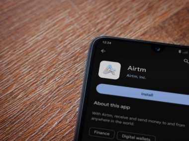 Lod, Israel - 16 Temmuz 2023: AirTM uygulama oyun mağazası sayfası ahşap zemin üzerinde akıllı telefon. Üst görünüm düzlüğü kopyalama alanı ile yatıyordu.