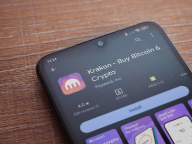 Lod, Israel - 16 Temmuz 2023: Kraken uygulama oyun mağazası sayfası ahşap arka planda akıllı telefon. Üst görünüm düzlüğü kopyalama alanı ile yatıyordu.