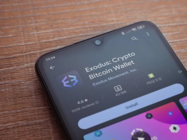 Lod, Israel - 16 Temmuz 2023: Exodus app playshop page on smartphone on wood background. Üst görünüm düzlüğü kopyalama alanı ile yatıyordu.