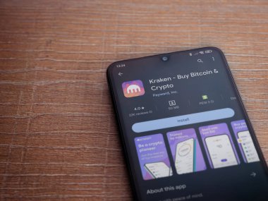 Lod, Israel - 16 Temmuz 2023: Kraken uygulama oyun mağazası sayfası ahşap arka planda akıllı telefon. Üst görünüm düzlüğü kopyalama alanı ile yatıyordu.