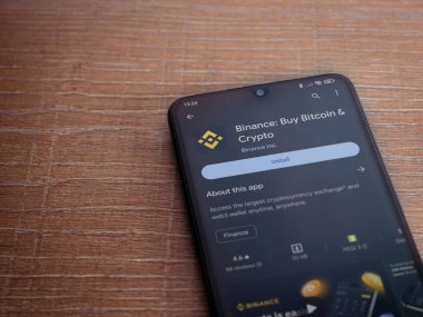 Lod, Israel - 16 Temmuz 2023: Binance uygulama oyun mağazası sayfası ahşap arka planda akıllı telefon. Üst görünüm düzlüğü kopyalama alanı ile yatıyordu.