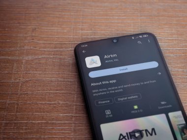 Lod, Israel - 16 Temmuz 2023: AirTM uygulama oyun mağazası sayfası ahşap zemin üzerinde akıllı telefon. Üst görünüm düzlüğü kopyalama alanı ile yatıyordu.