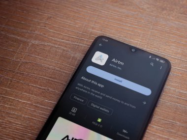 Lod, Israel - 16 Temmuz 2023: AirTM uygulama oyun mağazası sayfası ahşap zemin üzerinde akıllı telefon. Üst görünüm düzlüğü kopyalama alanı ile yatıyordu.