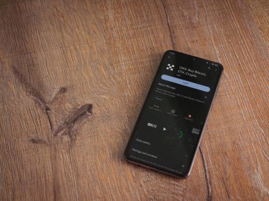 Lod, Israel - 16 Temmuz 2023: OKX uygulama oyun mağazası sayfası ahşap arka planda akıllı telefon. Üst görünüm düzlüğü kopyalama alanı ile yatıyordu.