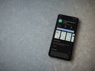 Lod, Israel - 16 Temmuz 2023: KuCoin uygulama oyun mağazası sayfası seramik taş zemin üzerinde akıllı telefon. Üst görünüm düzlüğü kopyalama alanı ile yatıyordu.