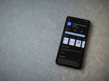 Lod, Israel - 16 Temmuz 2023: Seramik taş zemin üzerinde akıllı telefon ile sikke bazlı uygulama oyun mağazası sayfası. Üst görünüm düzlüğü kopyalama alanı ile yatıyordu.