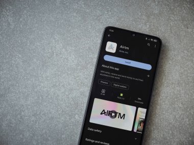 Lod, Israel - 16 Temmuz 2023: AirTM uygulama oyun mağazası sayfası seramik taş zemin üzerinde akıllı telefon. Üst görünüm düzlüğü kopyalama alanı ile yatıyordu.