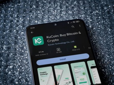 Lod, Israel - 16 Temmuz 2023: KuCoin uygulama oyun mağazası sayfası metalik arka planda akıllı telefon. Üst görünüm yatağını kapat.
