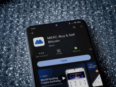 Lod, Israel - 16 Temmuz 2023: MEXC uygulama oyun mağazası sayfası metalik arka planda akıllı telefon. Üst görünüm yatağını kapat.