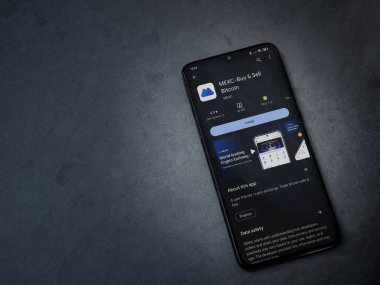 Lod, Israel - 16 Temmuz 2023: MEXC uygulama oyun mağazası sayfası kara mermer taşlı arka planda akıllı telefon. Üst görünüm düzlüğü kopyalama alanı ile yatıyordu.