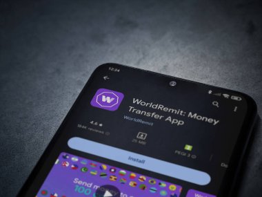 Lod, Israel - 16 Temmuz 2023: WorldRemit uygulama oyun mağazası sayfası kara mermer taşlı arka planda. Üst görünüm düzlüğü kopyalama alanı ile yatıyordu.