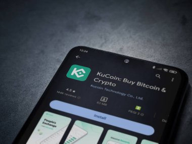 Lod, Israel - 16 Temmuz 2023: KuCoin uygulaması oyun mağaza sayfası kara mermer taşlı arka planda akıllı telefon. Üst görünüm düzlüğü kopyalama alanı ile yatıyordu.