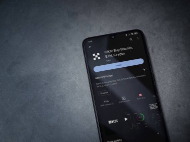 Lod, Israel - 16 Temmuz 2023: OKX uygulama oyun mağazası sayfası kara mermer taşlı arka planda akıllı telefon. Üst görünüm düzlüğü kopyalama alanı ile yatıyordu.