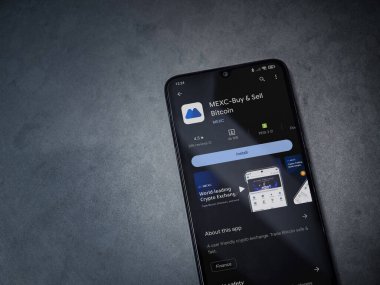 Lod, Israel - 16 Temmuz 2023: MEXC uygulama oyun mağazası sayfası kara mermer taşlı arka planda akıllı telefon. Üst görünüm düzlüğü kopyalama alanı ile yatıyordu.