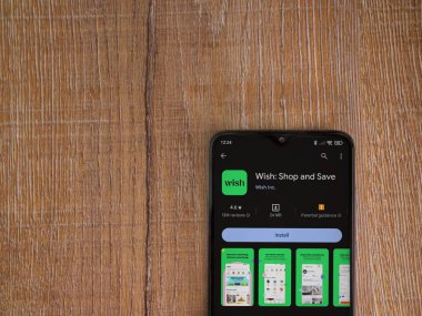 Lod, Israel - 16 Temmuz 2023: Ahşap arka planda akıllı telefondan dilek uygulaması oyun mağazası sayfası. Üst görünüm düzlüğü kopyalama alanı ile yatıyordu.