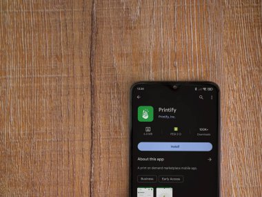 Lod, Israel - 16 Temmuz 2023: Uygulama oyun mağazası sayfasını ahşap arka planda akıllı telefondan bas. Üst görünüm düzlüğü kopyalama alanı ile yatıyordu.