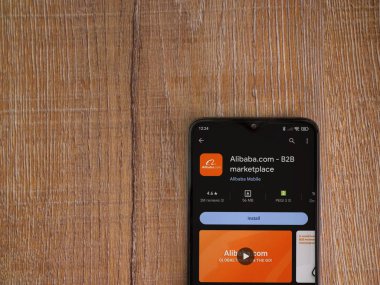 Lod, Israel - 16 Temmuz 2023: Alibaba.com uygulama oyun mağazası sayfası ahşap zemin üzerinde akıllı telefon. Üst görünüm düzlüğü kopyalama alanı ile yatıyordu.