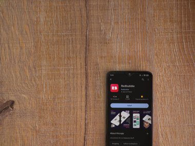 Lod, Israel - 16 Temmuz 2023: Ahşap arka planda akıllı telefon üzerine kırmızı baloncuklu uygulama oyun mağazası sayfası. Üst görünüm düzlüğü kopyalama alanı ile yatıyordu.