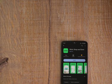 Lod, Israel - 16 Temmuz 2023: Ahşap arka planda akıllı telefondan dilek uygulaması oyun mağazası sayfası. Üst görünüm düzlüğü kopyalama alanı ile yatıyordu.