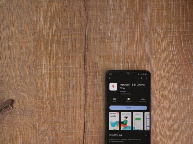 Lod, Israel - 16 Temmuz 2023: Instasell uygulama oyun mağazası sayfası ahşap zemin üzerinde akıllı telefon. Üst görünüm düzlüğü kopyalama alanı ile yatıyordu.