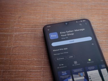 Lod, Israel - 16 Temmuz 2023: Etsy Seller uygulama oyun mağazası sayfası ahşap arka planda akıllı telefon. Üst görünüm düzlüğü kopyalama alanı ile yatıyordu.