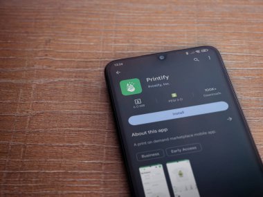 Lod, Israel - 16 Temmuz 2023: Uygulama oyun mağazası sayfasını ahşap arka planda akıllı telefondan bas. Üst görünüm düzlüğü kopyalama alanı ile yatıyordu.