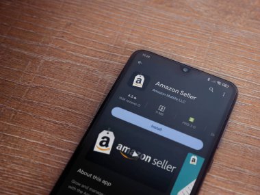 Lod, Israel - 16 Temmuz 2023: Amazon Seller uygulama oyun mağazası sayfası ahşap arka planda akıllı telefon. Üst görünüm düzlüğü kopyalama alanı ile yatıyordu.