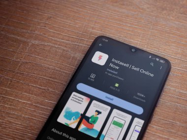 Lod, Israel - 16 Temmuz 2023: Instasell uygulama oyun mağazası sayfası ahşap zemin üzerinde akıllı telefon. Üst görünüm düzlüğü kopyalama alanı ile yatıyordu.