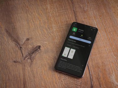 Lod, Israel - 16 Temmuz 2023: Uygulama oyun mağazası sayfasını ahşap arka planda akıllı telefondan bas. Üst görünüm düzlüğü kopyalama alanı ile yatıyordu.