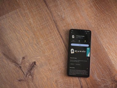 Lod, Israel - 16 Temmuz 2023: Amazon Seller uygulama oyun mağazası sayfası ahşap arka planda akıllı telefon. Üst görünüm düzlüğü kopyalama alanı ile yatıyordu.