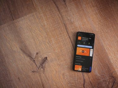 Lod, Israel - 16 Temmuz 2023: Alibaba.com uygulama oyun mağazası sayfası ahşap zemin üzerinde akıllı telefon. Üst görünüm düzlüğü kopyalama alanı ile yatıyordu.