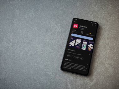 Lod, Israel - 16 Temmuz 2023: Kırmızı baloncuklu uygulama oyun mağazası sayfası seramik taş zemin üzerinde akıllı telefon. Üst görünüm düzlüğü kopyalama alanı ile yatıyordu.