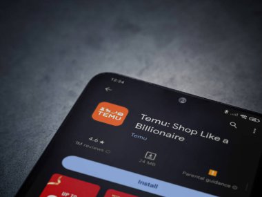 Lod, Israel - 16 Temmuz 2023: Koyu mermer bir arka planda akıllı telefondan Temu app oyun mağazası sayfası. Üst görünüm düzlüğü kopyalama alanı ile yatıyordu.