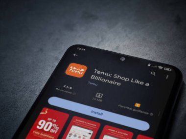 Lod, Israel - 16 Temmuz 2023: Koyu mermer bir arka planda akıllı telefondan Temu app oyun mağazası sayfası. Üst görünüm düzlüğü kopyalama alanı ile yatıyordu.
