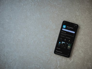 Lod, Israel - July 16,2023: Home Assistant app play store page on smartphone on ceramic stone background. Top view flat lay with copy space.