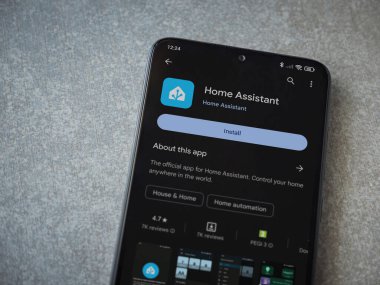 Lod, Israel - July 16,2023: Home Assistant app play store page on smartphone on ceramic stone background. Top view flat lay with copy space.