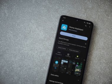 Lod, Israel - July 16,2023: Home Assistant app play store page on smartphone on ceramic stone background. Top view flat lay with copy space.