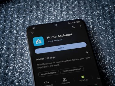 Lod, Israel - July 16,2023: Home Assistant app play store page on smartphone on a metallic background. Close up top view flat lay.