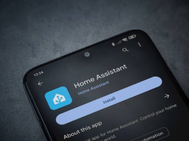 Lod, Israel - July 16,2023: Home Assistant app play store page on smartphone on a dark marble stone background. Top view flat lay with copy space.