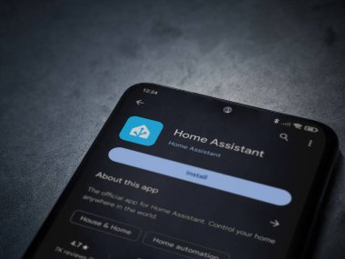 Lod, Israel - July 16,2023: Home Assistant app play store page on smartphone on a dark marble stone background. Top view flat lay with copy space.